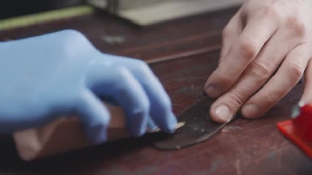 Professioneller Gerber schärft den Gürtel. Der Ledermeister bastelt einen Gürtel - Filmmaterial, Video