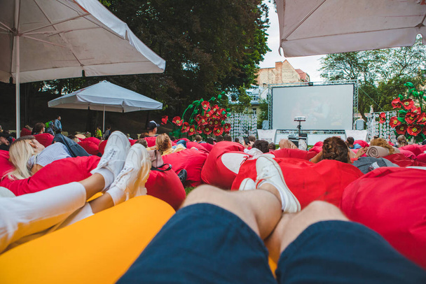 άνθρωποι στο δημόσιο πάρκο της πόλης βλέποντας ταινία σε υπαίθριο κινηματογράφο. ρομαντική ημερομηνία - Φωτογραφία, εικόνα