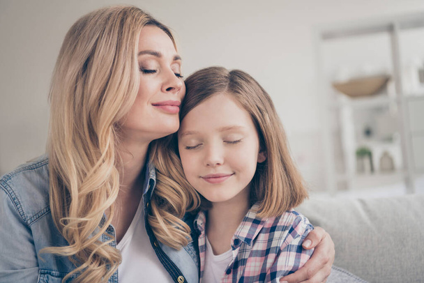 Closeup photo of domestic attractive blond lady mommy daughter sitting comfy couch hold arms eyes closed overjoyed stay home safety quarantine hugging best friends living room indoors - Photo, Image