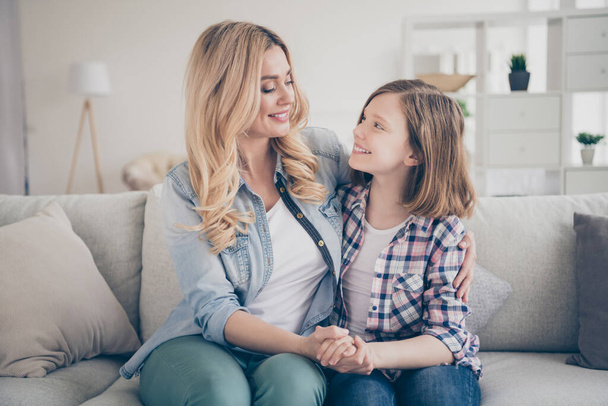 Photo of domestic attractive blond lady mommy daughter sitting comfy couch hold arms look eyes stay home quarantine spend weekend together hugging best friends living room indoors - Foto, Bild