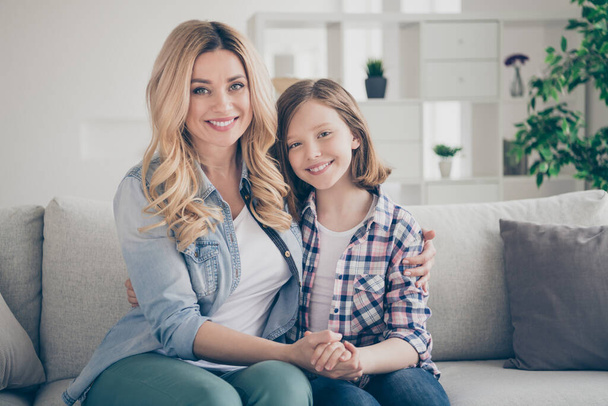 Photo of domestic charming blond lady mommy daughter sitting comfy couch hold arms stay home quarantine spend weekend together hugging best friends living room indoors - Фото, зображення