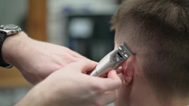 Young mans haircut in Barbershop. Close-up of master clipping hair with clipper - Video