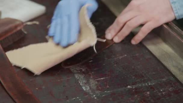 Um artesão de couro esfrega as bordas de um cinto. O mestre está usando a ferramenta de massagem
. - Filmagem, Vídeo