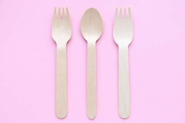 eco friendly disposable kitchenware utensils on pink background. wooden forks and spoons. ecology, zero waste concept. top view. flat lay - Valokuva, kuva