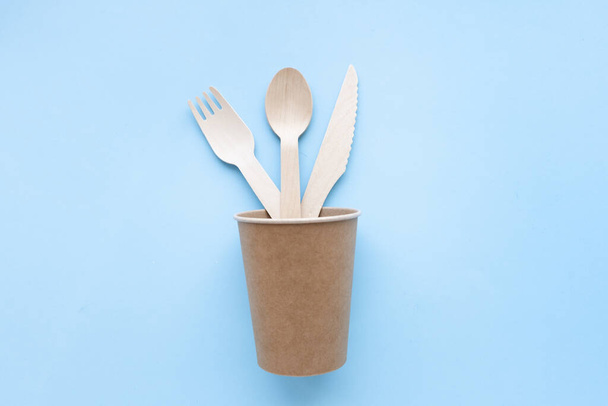 eco friendly disposable kitchenware utensils on blue background. wooden forks and spoons in paper cup. ecology, zero waste concept. top view. flat lay - Zdjęcie, obraz