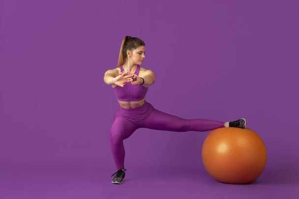 Beautiful young female athlete practicing on purple studio background, monochrome portrait - Φωτογραφία, εικόνα