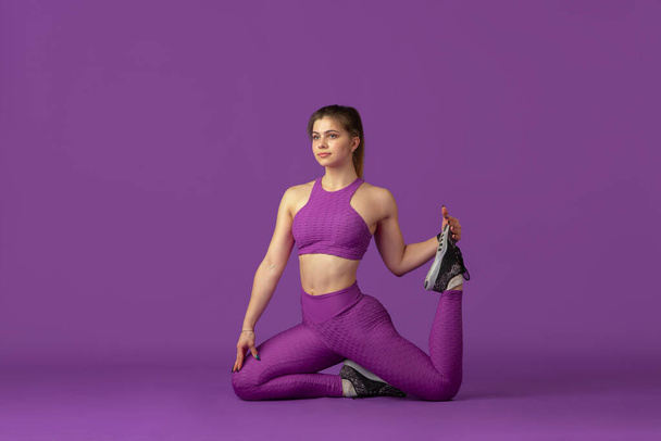 Beautiful young female athlete practicing on purple studio background, monochrome portrait - Valokuva, kuva