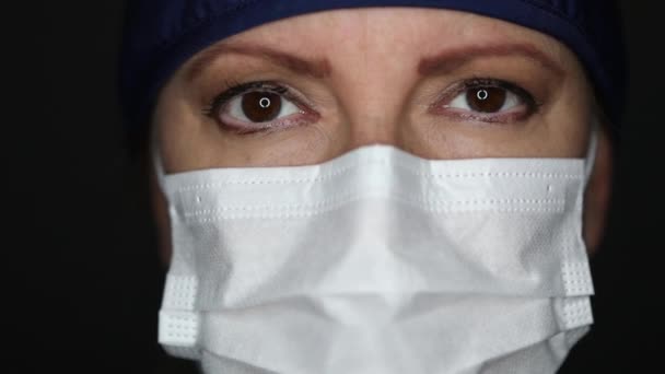 Female Doctor or Nurse Wearing Surgical Mask and Cap Looking Around and Into The Camera. - Filmagem, Vídeo