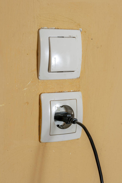 Dirty power outlet on a yellow wall. - Φωτογραφία, εικόνα