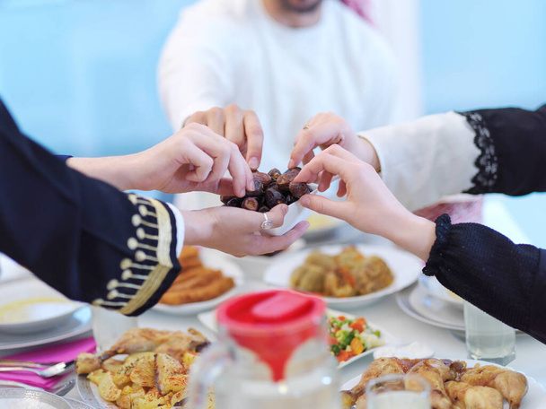 Eid Mubarak Muslim family having Iftar dinner eating dates to break feast. Eating traditional food during Ramadan feasting month at home. The Islamic Halal Eating and Drinking at modern western Islam - Fotó, kép