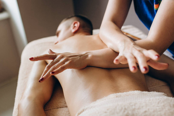 Mężczyzna cieszący się relaksującym masażem pleców od żony. Medycyna alternatywna i domowy temat spa. Koncepcja zdrowia i relaksu.Skup się na rękach - Zdjęcie, obraz