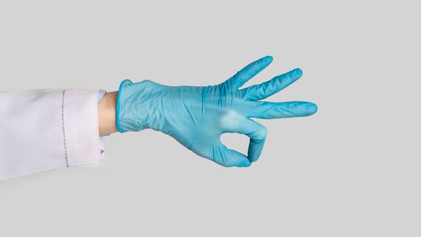 Female hand in rubber glove shows ok sign - Foto, imagen