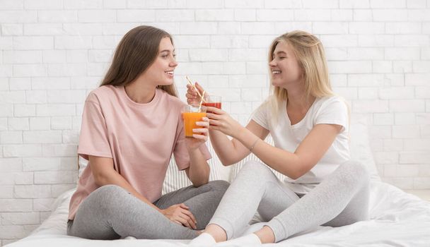 Kaksi tyttöystävää puhuu, hymyilee ja juo tuoretta smoothie
 - Valokuva, kuva