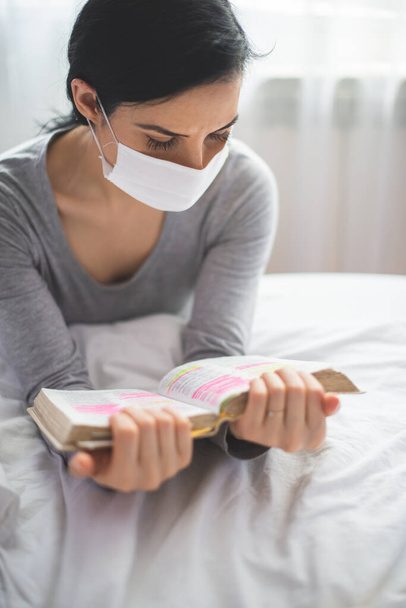 Quarantined woman with mask reading from bible and praying - Foto, Imagem