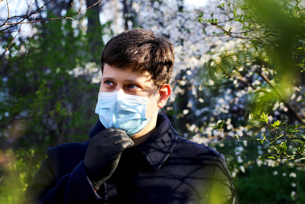 Muž v modré lékařské masce a černé rukavice venku. - Fotografie, Obrázek