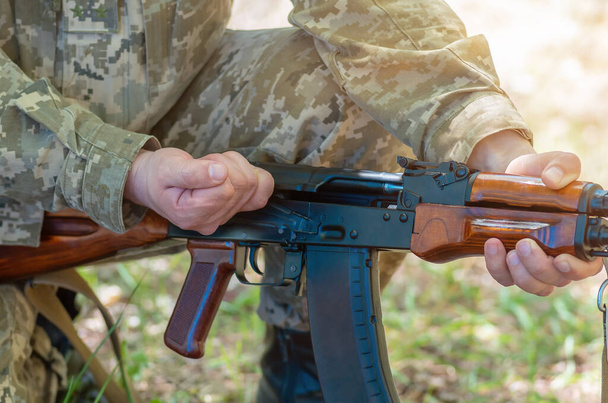 Kalashnikov automatisch machinegeweer close-up in de handen van het leger. Mannelijke handen laden een Kalashnikov aanvalsgeweer. Avtomatische geweerclose-up - Foto, afbeelding