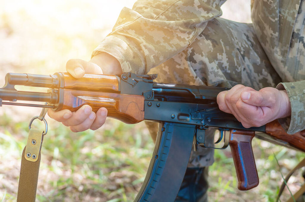カラシニコフ自動機関銃は軍の手の中に閉じ込められている。男性の手はカラシニコフのアサルトライフルを充電します。自動小銃クローズアップ - 写真・画像