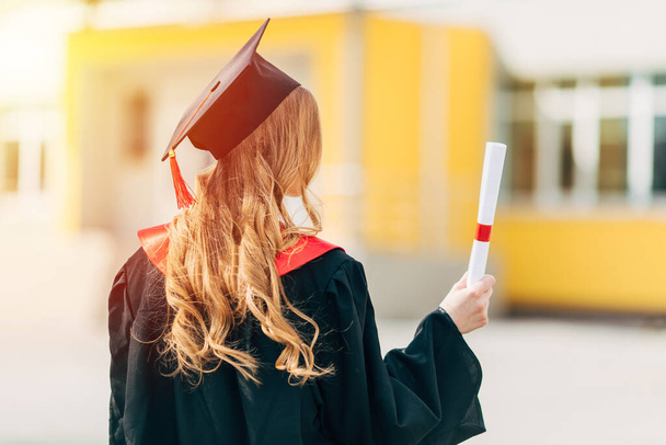 Día de graduación, vista trasera, un joven estudiante con una gorra de graduación y vestido con un diploma. El concepto de éxito
 - Foto, Imagen