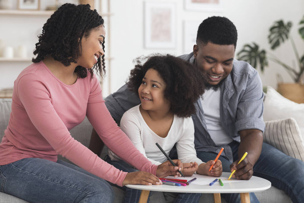 heureux noir parents dessin avec leur petite fille à la maison
 - Photo, image