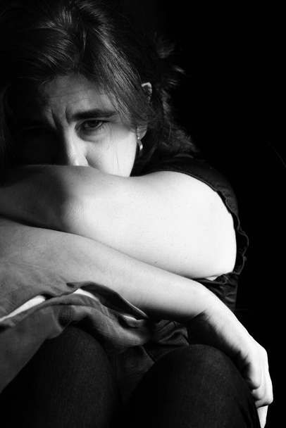 Sad and lonely woman with a thoughtful expression - Black and white portrait on a black background - Fotó, kép