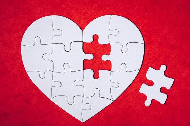 Heart-shaped jigsaw puzzle on color background. Puzzle heart on wooden background. A missing piece of the heart puzzle. Heart shape jigsaw puzzle. Puzzles in the shape of a heart.  - 写真・画像
