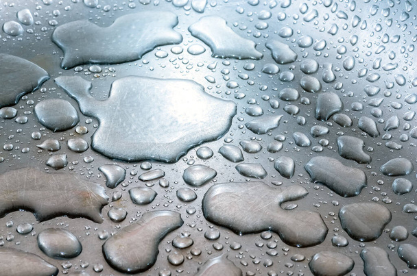 kapky vody leží na stříbřitém kovovém poškrábaném povrchu. Metalické pozadí - Fotografie, Obrázek