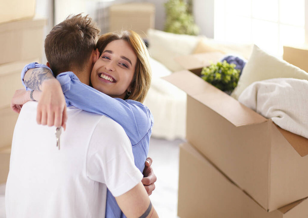 Happy couple moving house, boxes around, holding keys - Fotografie, Obrázek