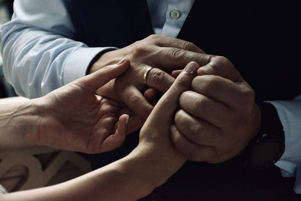 Женщина держит мужчин за руки обручальным обручальным кольцом, интимный трогательный момент только что супружеской пары, новой семьи
 - Фото, изображение