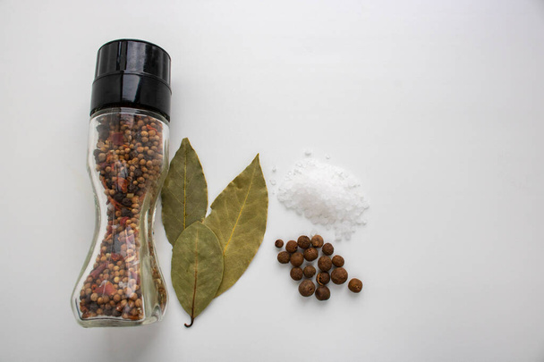 Ein Glas mit Gewürzen, Lorbeerblatt, Salz auf weißem Hintergrund in der Küche. - Foto, Bild