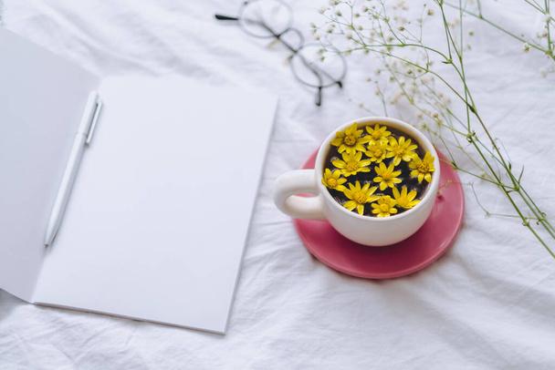 Cup with yellow flowers on a white bed - Foto, immagini