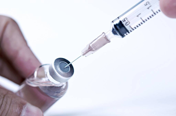 Bir doktorun elinde cam bir ilaç şişesi. Aşısı olan bir şişe hastanede el ele tutuşur. Teknisyen aşıyı hazırlar. Aşılama yoluyla virüslerin yayılmasını önlemek. - Fotoğraf, Görsel