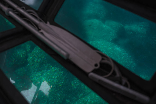vista del agua verde y las rocas desde el suelo transparente de un barco, con remos
. - Foto, Imagen
