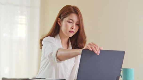 Young adult Asian woman work at home office, open laptop computer and start working. Work from home life, information technology, domestic lifestyle or internet remote working concept. Handheld camera - Footage, Video