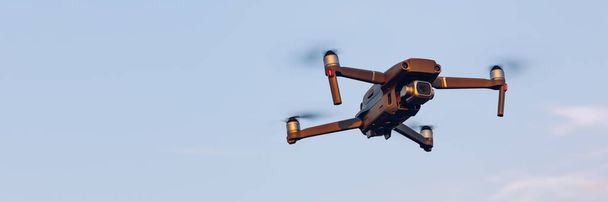 Lennokki lentää maiseman yllä. UAV drone kopteri lentää digitaalikameralla. Lennokki lentää pilvisellä sinisellä taivaalla. Kopteri lentää pellon yli.
. - Valokuva, kuva