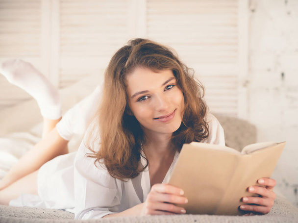 beautiful blond woman reading book in the bed. Relaxing concept - Fotó, kép
