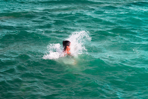 Девушка исчезает в волне, прыгает и погружается в освежающее море, океан, в жаркий летний день
 - Фото, изображение
