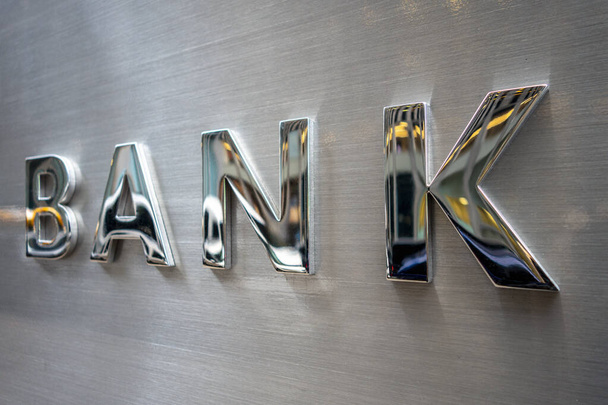Big soild glossy chrome metal BANK text on a brushed steel wall with regflection - Photo, Image