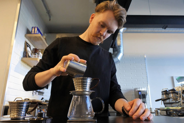 Kahveci yetişkin bir adam (25 yaşında) kafede kahve hazırlıyor. Gerçek insanlar. Boşluğu kopyala - Fotoğraf, Görsel