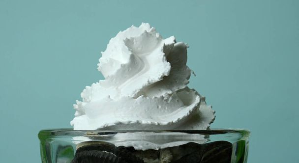 Закрыть Whipping сливки на печенье мороженое и крем синий фон, Front view Концепция питания
 - Фото, изображение