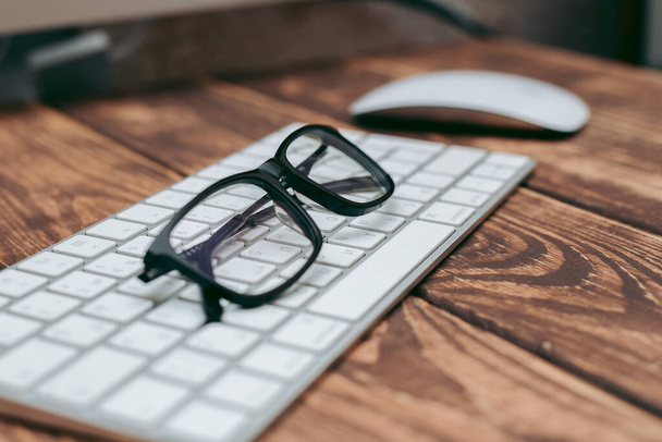 Görüş ve görüş düzeltme için gözlük ve klavyedeki ahşap masadaki bilgisayardan koruma - Fotoğraf, Görsel
