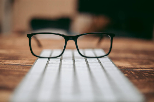 Glasses for sight and vision correction and protection from computer on the wooden table on the keyboard - Фото, зображення
