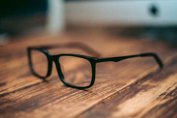 Szemüveg látásjavításhoz és látásjavításhoz, valamint számítógép elleni védelem a fa asztalon - Fotó, kép