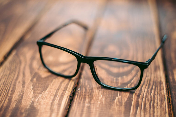 Γυαλιά για διόρθωση όρασης και όρασης και προστασία από τον υπολογιστή στο ξύλινο τραπέζι - Φωτογραφία, εικόνα