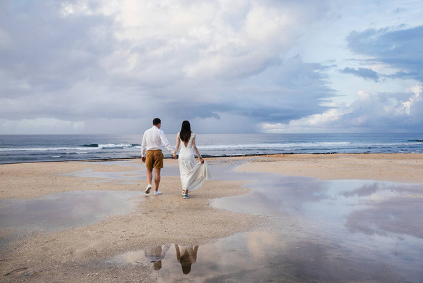 couple in love - bride and groom  on the wedding day hug and kiss on the beach by the ocean on the exotic Asian island of Bali in Indonesia, incredible landscape - Foto, Imagem