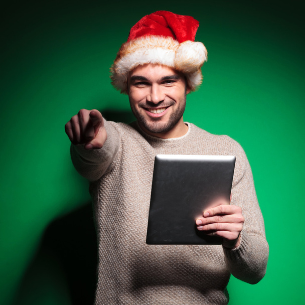 Père Noël homme pointe du doigt tout en lisant sur la tablette
 - Photo, image