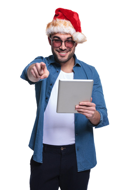 Man with santa hat is pointing while reading on tablet - Photo, Image