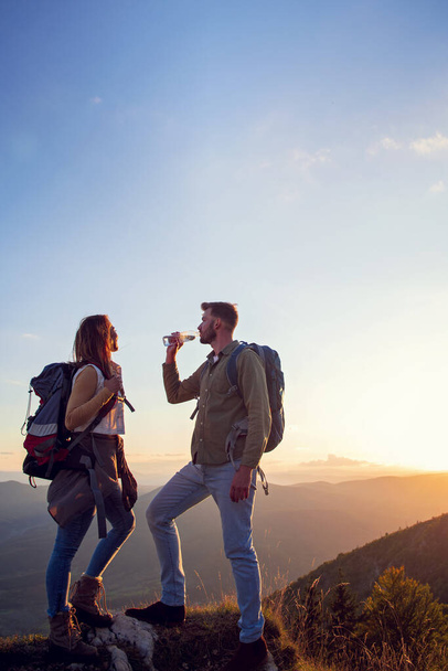 Young Couple Hiking On The Peak of Mountain drinking water - Photo, Image