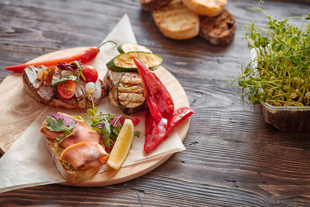 Bruschetta with fish, meat, vegetables and cheese on a wooden Board. Traditional Italian appetizer or appetizer, antipasto. - Fotó, kép