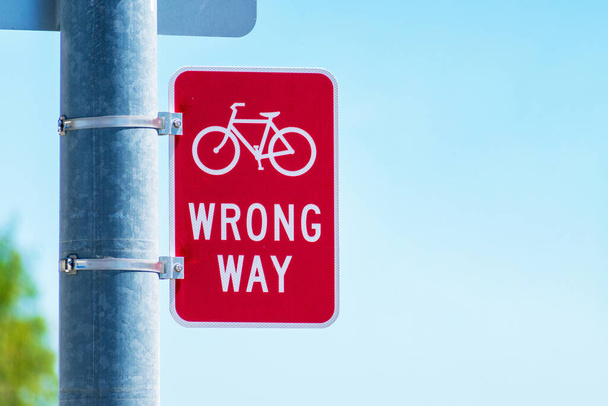 Rode fiets verkeerd bewegwijzerd bord op straatpaal op verkeerd rijdend fietsverkeer. - Foto, afbeelding