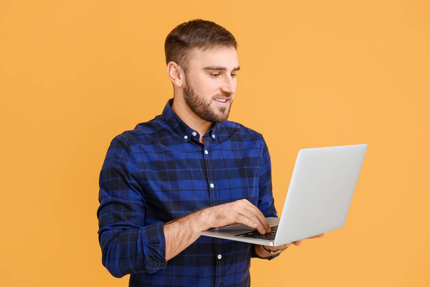 Programador masculino con portátil sobre fondo de color - Foto, Imagen